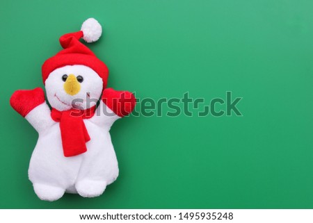 Toy smiling snowman on a green background. Copy Space.