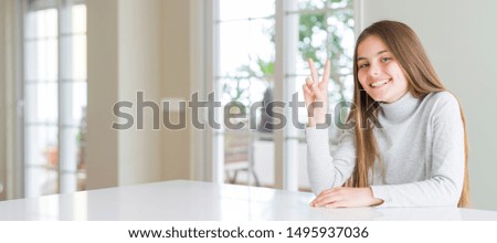 Wide angle picture of beautiful young girl kid wearing casual sweater showing and pointing up with fingers number two while smiling confident and happy.