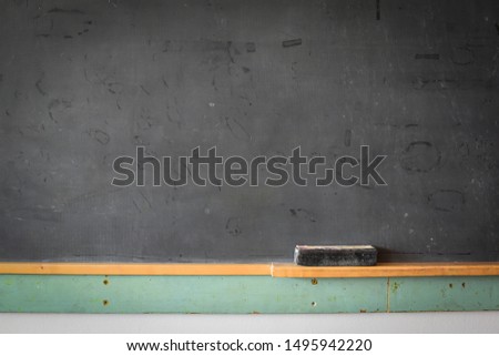 close up of blackboard with eraser on wooden stand green wall below chalk board background