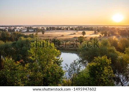 Amazing morning landscape. Horizon line, blue clear sky, soft sunlight, green trees and foggy meadows, river water. Aerial view of countryside nature. Horizontal color photography.