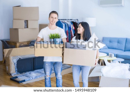 Young beautiful couple moving cardboard boxes at new home