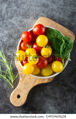 Fresh, organic yellow and red tomatoes in plate over dark background.