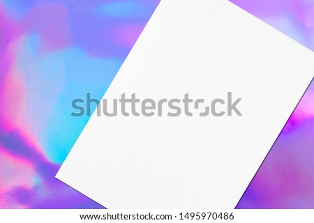 Close up of empty white rectangle poster mockup lying diagonally with soft shadow on holographic background. Flat lay, top view. Open composition.