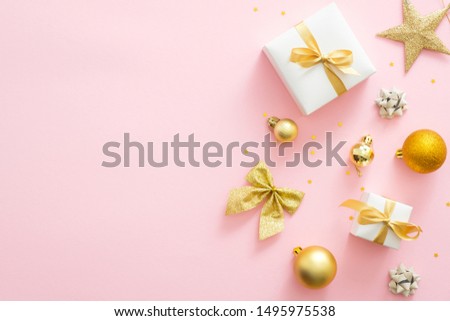Pink Christmas background with golden decorations, gift boxes, balls, confetti, bow, star. Christmas minimal stylish composition, flat lay, top view, overhead. Christmas card mockup with copy space