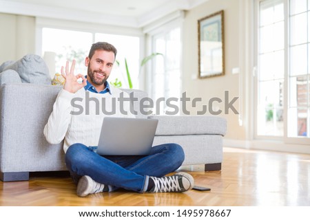 Handsome man wearing working using computer laptop doing ok sign with fingers, excellent symbol