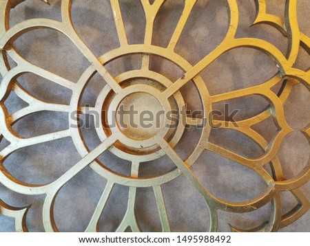 Gold painted laser cut metal, steel or stainless decorated on a beautiful gray wallpaper. 