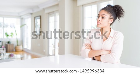 Wide angle of beautiful african american woman with afro hair looking to the side with arms crossed convinced and confident Royalty-Free Stock Photo #1495996334