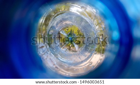 Long background with a plastic blue bottle with water drops inside