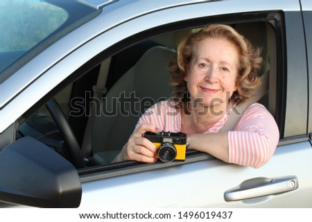 Mature female driver holding vintage camera
