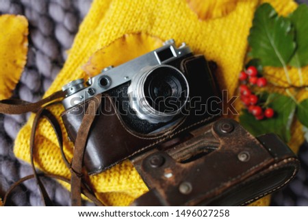 Autumn flat lay background. Top view of vintage photo camera, yellow sweater, knitted blanket and pumpkin, fall leaves. Happy thanksgiving autumn background
