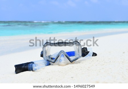 Snorkeling equipment (snorkel and mask) lie on the white sand on the beach, Indian Ocean, Maldives