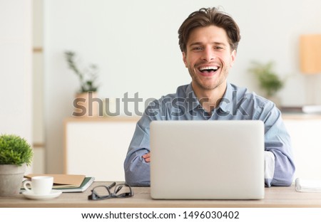 Man Sitting At Laptop And Laughing Looking At Camera Indoor. Empty Space For Text Royalty-Free Stock Photo #1496030402