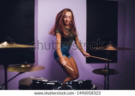 Photograph of a female drummer playing a drum set on stage.