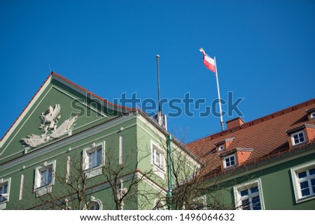Polish national flags on a green major building in a slight breeze