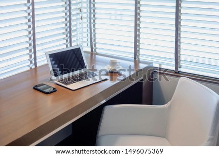 Modern workspace with light streaming in from mini blinds
