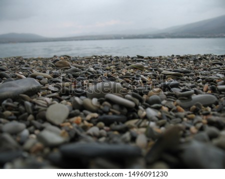 a scattering of smooth oval gray stones on the shore of the undulating sea against the dark sky