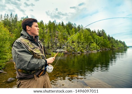 Fisherman using rod fly fishing in mountain river autumn splashing water.