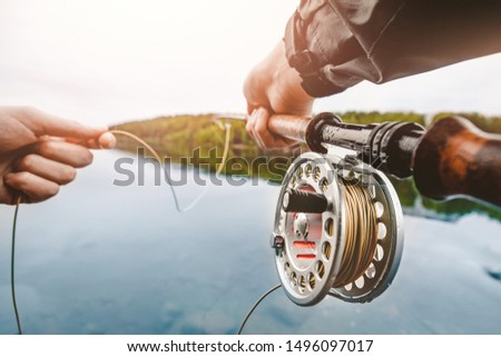 Coil of fly fishing rope, man hands holding rod. Royalty-Free Stock Photo #1496097017