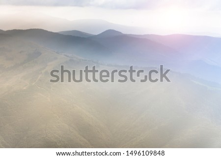 Landscape of mountain range with visible silhouettes through the morning colorful fog. Sunrise in the mountains. Filtered image:cross processed retro effect. Perfect nature background pictures.
