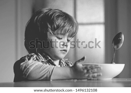 Kid boy eating healthy food at home. Good morning in Happy family. Little boy sitting at the table and eating milk snack