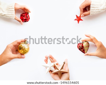 People are holding New Year decoration - balls, hearts, stars on white background. Top view on decoration for Christmas tree. Copy space.