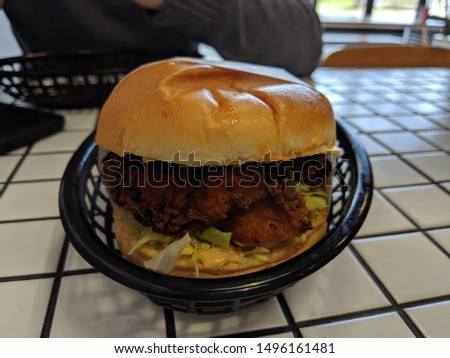 American style southern fried chicken with lettuce and relishes on a burger bun