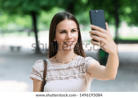 Young woman using her mobile phone to take a selfie portrait