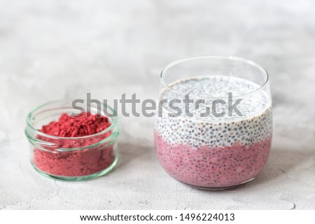 Chia seed pudding with almond milk, yogurt and pink pitaya dragon fruit powder in a glass. Superfood and vegan food concept. Gray background. Copy space, selective focus.