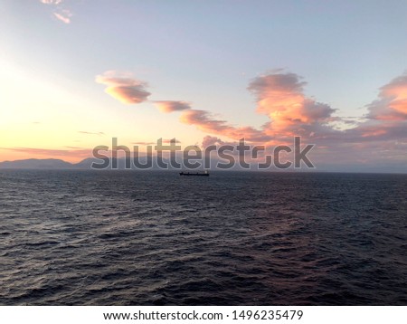 Sunset in the Mediterranean Sea. Dark sea against the sky with clouds, on the horizon a ship. Horizontal, free space.