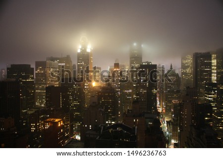 Night view of New York City with the buiding lights translucid by the fog.