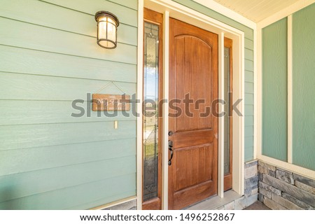 A home with brown front door sidelight green wood all and stone brick wall