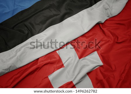 waving colorful flag of switzerland and national flag of estonia. macro