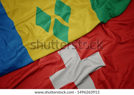 waving colorful flag of switzerland and national flag of saint vincent and the grenadines. macro