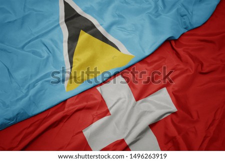 waving colorful flag of switzerland and national flag of saint lucia. macro