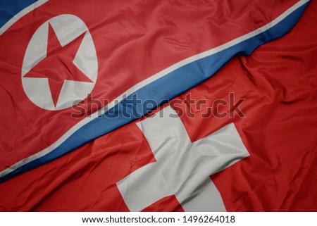 waving colorful flag of switzerland and national flag of north korea. macro