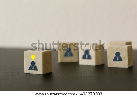 Leader with idea and innovation. Marble block with human symbol and light bulb icon standing out from the crowd. Successful business team leader concept
