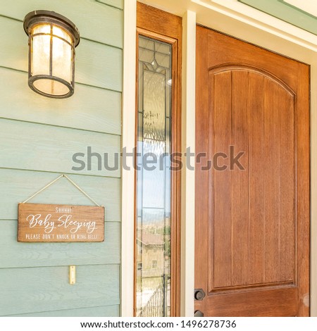 Square A home with brown front door sidelight green wood all and stone brick wall