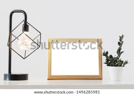 metal black lamp, woodenframe and plant in white interior