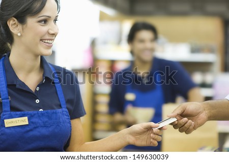 Closeup of a hand giving female employee loyalty card in supermarket Royalty-Free Stock Photo #149630039