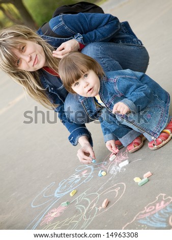 A cute little girl drawing with mom a sketch on a pavement
