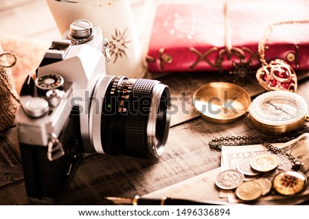 vintage items, pen red book, coins money, compass and retro photo film camera on wood background.