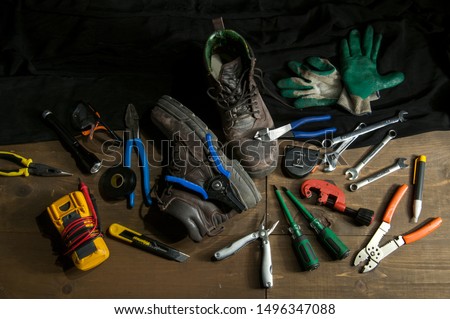 Electrician tools and gear on a work bench in a low key light photography  Royalty-Free Stock Photo #1496347088