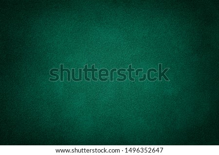 Dark green matte background of suede fabric, closeup. Velvet texture of seamless deep emerald leather. Felt material macro with vignette. Royalty-Free Stock Photo #1496352647