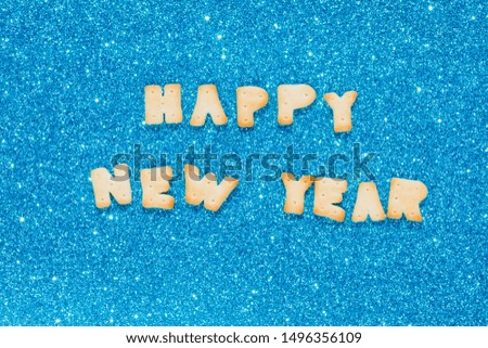 Happy new year written by cookies on blue seamless glitter sparkle pattern texture. Letters fonts from cookies. 