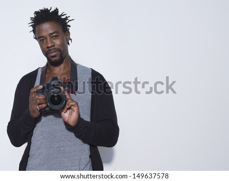 Portrait of an African American male photographer holding camera in studio