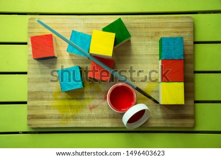 

multi-colored wooden cubes on a green background and red paint