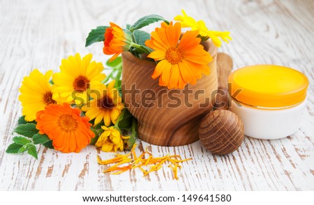 mortar and pestle with Calendula flowers on a wooden background