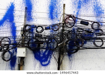 Street art. Public electricity poles, with people bringing the color to splash until spread throughout. The pole with messy cables beside the wall splashed with color was made by an unknown person.