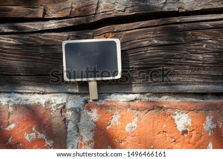 An information sign stands on a brick and wooden obsolete wall