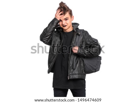 Unhappy teen boy student with backpack in style of punk goth dressed in black, isolated on white background. Upset Teenager Back to school. Sad child with spooking makeup.